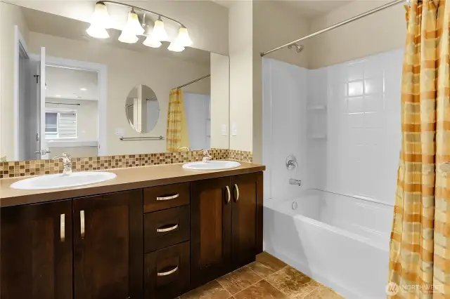 A full bath is centrally located between the bedrooms and a tall vanity counter with two oval sinks.   The bathtub/shower is located in a separate room from the toilet for privacy.