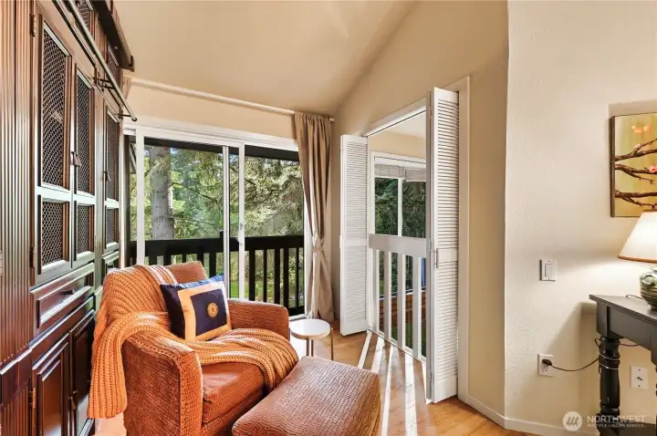 Seating area in primary bedroom has louvered doors to look below into living room and a Juliet balcony to enjoy the view.