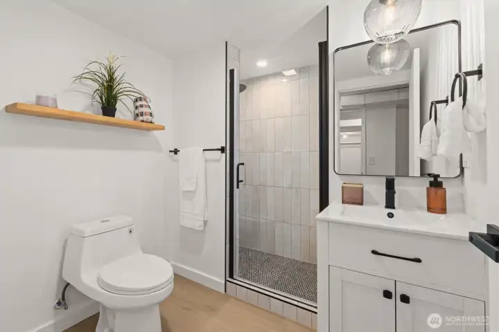 Updated 3/4 bath with new:vanity sink, Lit shower niche, floating shelf, floor to ceiling tile, penny tile, mirror, hardware and lighting sconce.