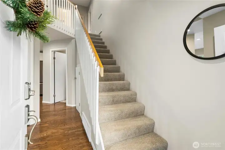 Entryway features warm hardwood flooring and a charming spindle rail design.