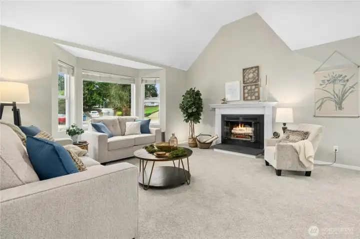 Living room features, vaulted ceilings, large windows, and fireplace!