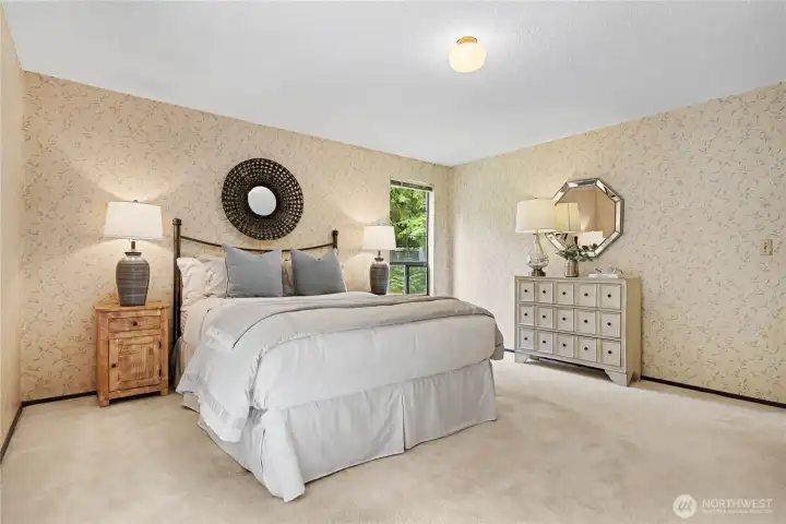 Spacious primary bedroom with large windows, soft natural light, and peaceful views of the surrounding greenery.