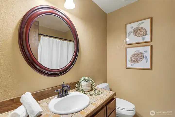 Main bathroom with tile countertop, warm finishes, and a clean, well-maintained layout.