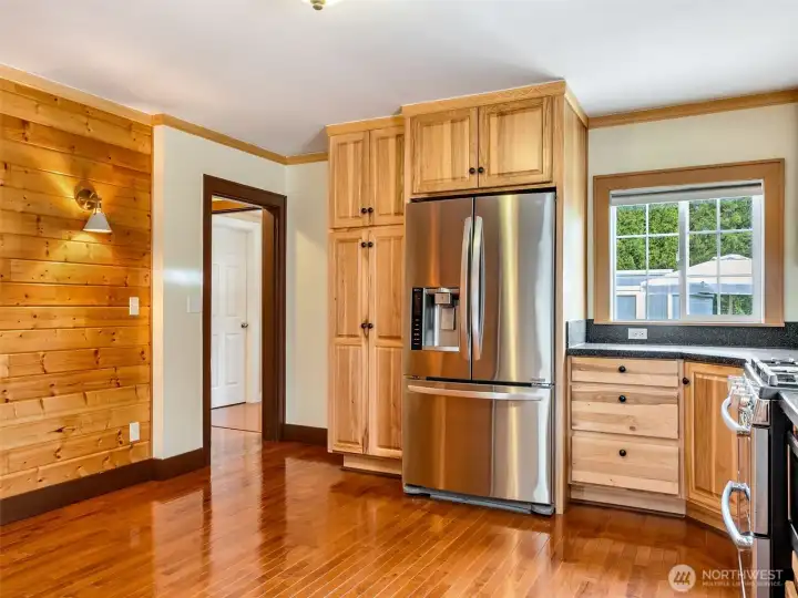 Dining area within the kitchen and hardwood flooring leading to the other areas of the home