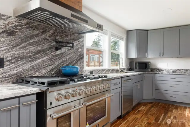 Custom kitchen with gourmet stove and custom fan hood.