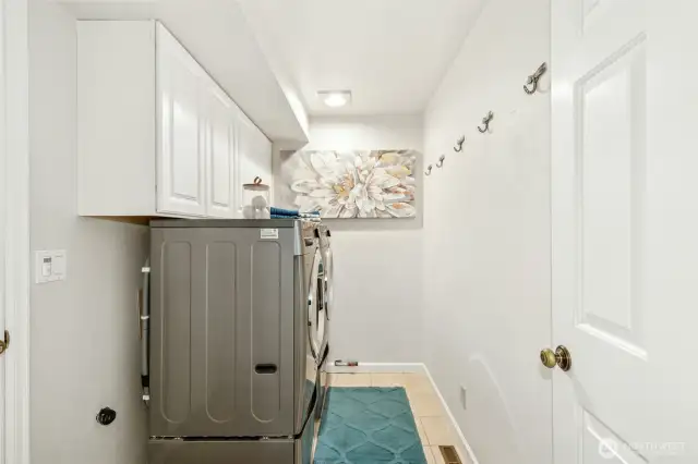 Utility room with a gas, dryer hook-up and functional cabinetry. Door leads out to the garage.
