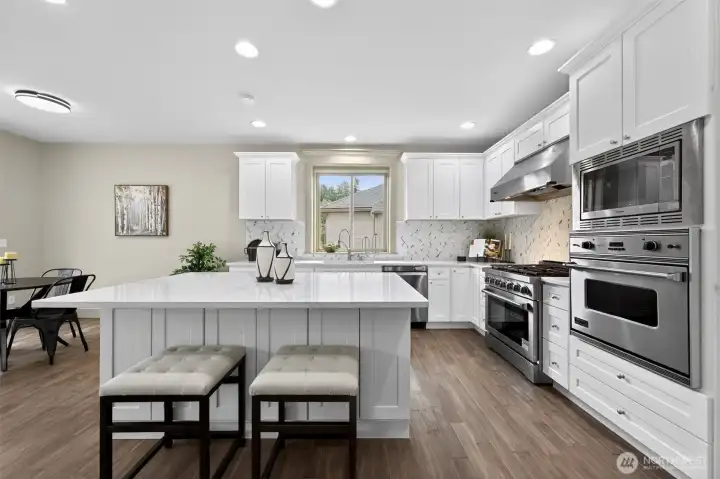 Fresh, bright kitchen with white cabinets, a large island, stainless steel appliances, and plenty of counter space.