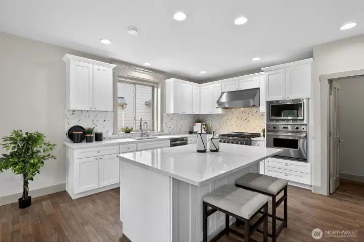 A home chef's dream and delight! Abundance of cabinets that boast  generous prep space, extensive counters, and center island with barstool seating