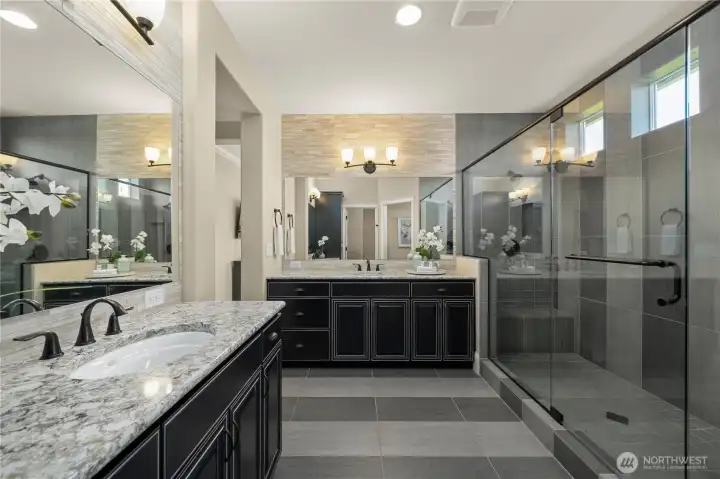 The spa-like primary bath offers two vanities with Quartz, stunning cabinetry, statement tile feature walls, tile flooring and shower.