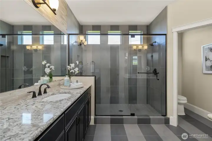 The oversized fully tiled walk-in shower features dual shower heads, a bench and a niche. Plus an upgraded glass enclosure.