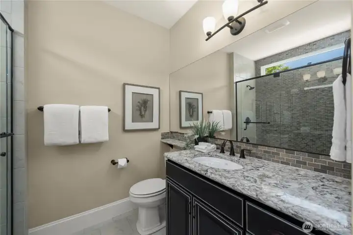 Private guest suite bath offers Quarts counters with backsplash, tile shower and floors.