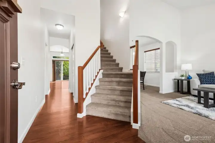 Soaring ceilings, abundant natural light, and an inviting open staircase create a warm welcome