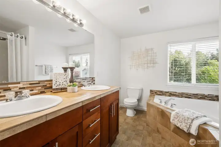 Spacious primary ensuite featuring dual sinks, soaking tub, and abundant natural light