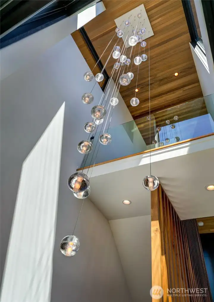 A dramatic three-story entry, illuminated by statement lighting and connected by warm wood stair treads, establishes an atmosphere that is both sophisticated and inviting.