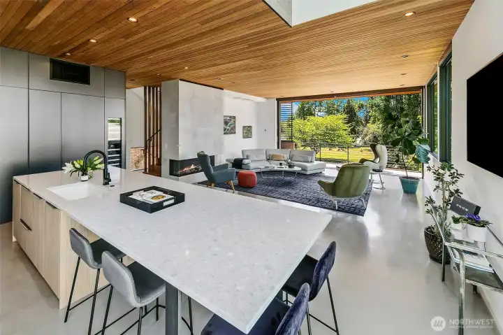 The chef's kitchen flows seamlessly into the great room, where a full-length Fleetwood sliding glass wall opens completely to the outdoors.