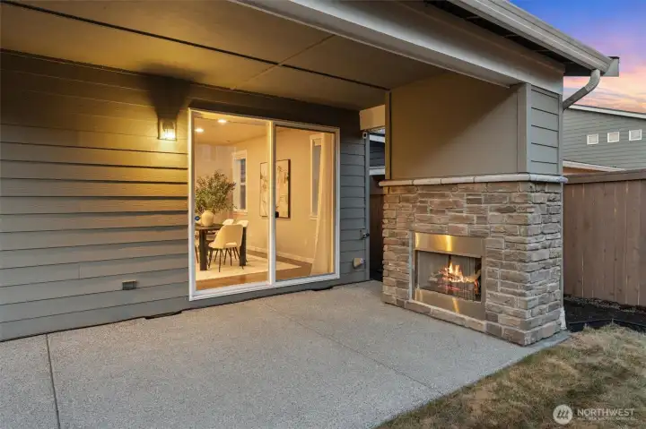A covered patio with a gas fireplace surrounded in stone gives you room to dine, unwind, and connect year-round.