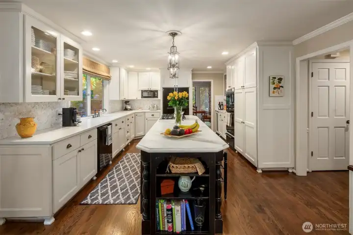 On the other side of the ovens and warming drawer are more glass cabinets and a wine refrigerator.