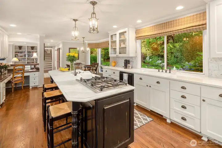 Another view of the kitchen showing the back staircase, the family room and eating nook. Also a built in desk with more storage above. The door into the garage is to the left just before reaching the stairs.
