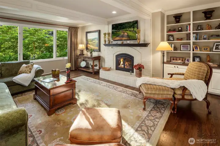 Family room adjacent to the kitchen with fireplace, more cabinetry and display shelves.