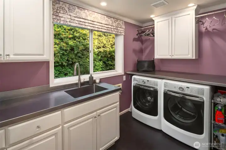 Laundry room has stainless steel countertops and a marmoleum floor.