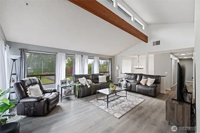 Step into a living space that instantly welcomes you with soaring vaulted ceilings and rich, exposed wood beams that add both architectural interest and warmth.