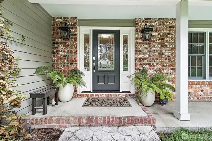 Circular driveway leads to a welcoming entry, with new exterior light fixtures and a brick facade.