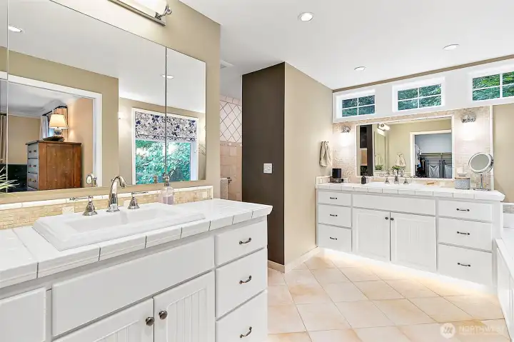 Dual vanities with large mirrors, polished chrome fixtures, and sleek hardware offer both style and functionality, while the radiant heated flooring adds a touch of everyday luxury and comfort.