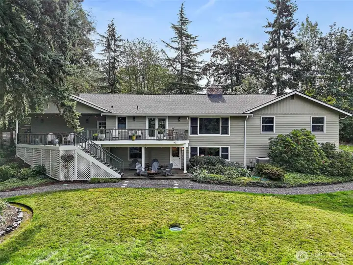 The back of the home showcases an expansive deck overlooking the beautifully landscaped, oversized lot, perfect for outdoor dining, entertaining, or simply taking in the peaceful surroundings. With multiple seating areas and a spacious yard, this property offers plenty of room to relax, play, and enjoy the best of indoor-outdoor living.