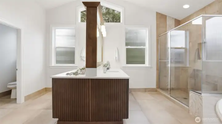 Large windows bring in natural light, private water closet, and large walk-in shower in this thoughtfully designed primary bathroom.