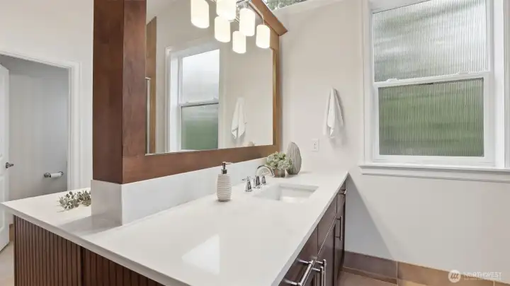 Quartz countertop, mirror, and abundant light highlight each side of this dual vanity.