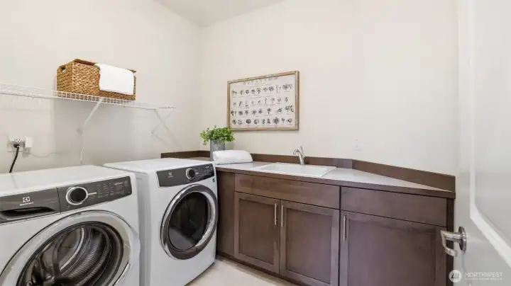 Convenient upper level laundry room with utility sink and an abundance of work space