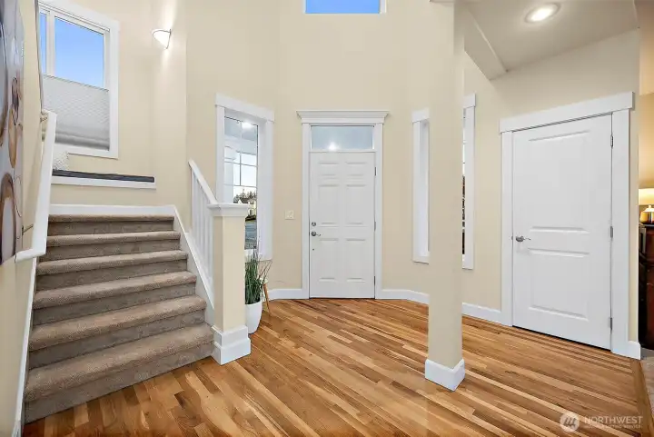 Grand foyer brings in so much light as you enter the house, coat closet just to the right of front door, and formal living room next to closet; carpeted staircase leads you upstairs with handrail.