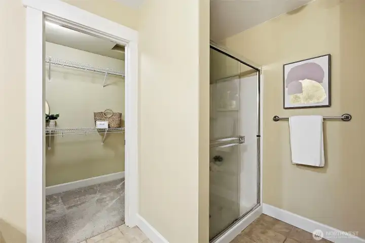 Walk-in shower with glass sliding doors to right of the walk-in closet entrance.