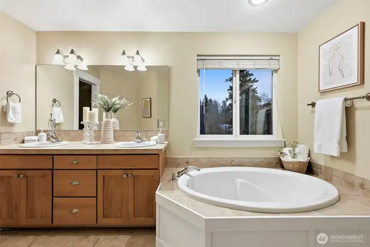 Primary bedroom en-suite bathroom with soaking tub and walk-in shower, double-sink vanity and window brings in extra light.