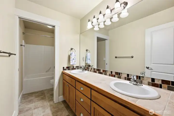 Second full bathroom located upstairs. Double sink vanity and large mirror. Shower/tub and toilet are separated from vanity area with pocket door.