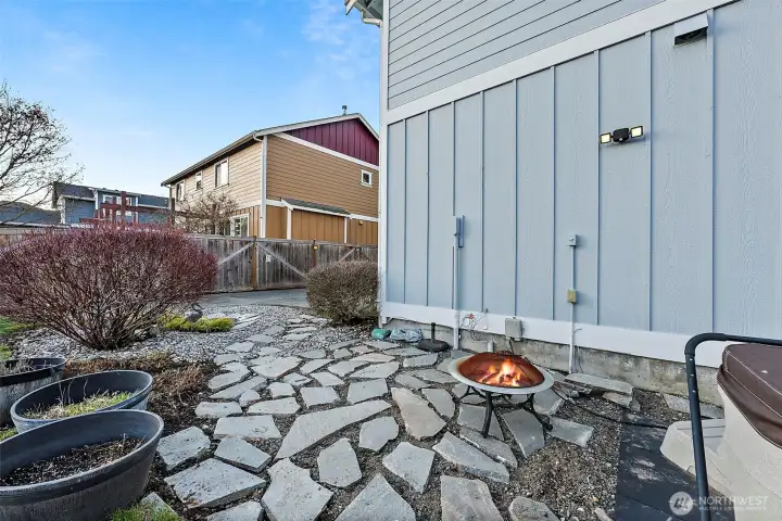 stone pavers lead from driveway patio to the hot tub around side of house from garage in backyard.