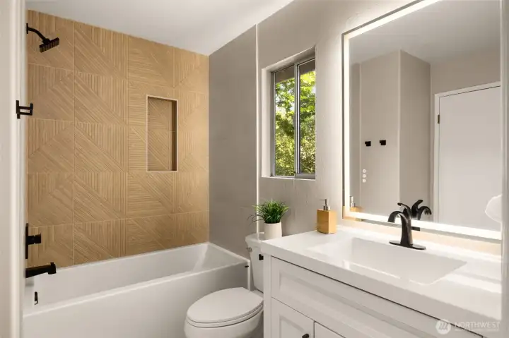 Desirable "Jack and Jill" bathroom, fully renovated in 2026, features a quartz vanity with soft-close drawers, LED backlit mirror, floor-to-ceiling tile surround, and a brand-new tub/shower. Large-format porcelain floor tile adds a modern, polished finish.