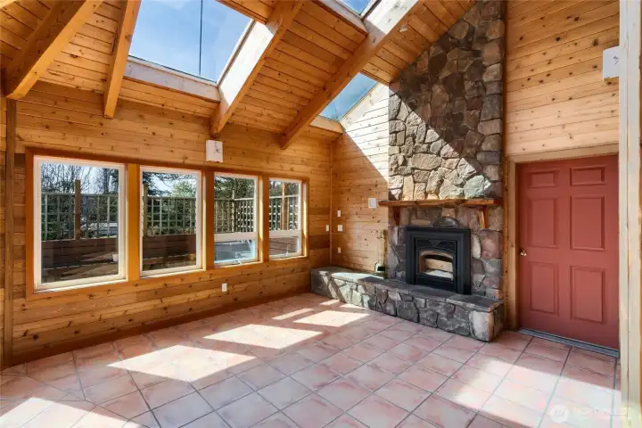 Warm and inviting atrium chalet like living room with rock fireplace looks out to deck for outdoor entertaining
