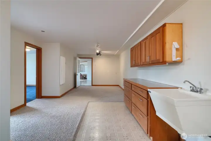 Large hallway with built-in shelves, cabinets and working sink next to laundry area