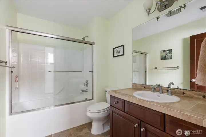 Full Bathroom next to the 3rd Bedroom, with tile vanity and floor, plus a tub/shower enclosure with double glass doors.
