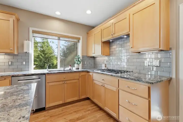 The updated kitchen shines with honey-toned Shaker style maple cabinetry, sparkly slab granite countertops, stainless steel appliances, and  hardwood floors.