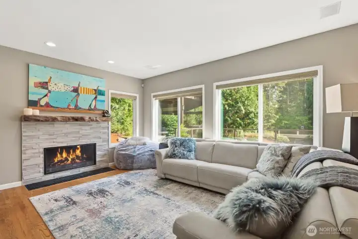 The adjacent family room with its walls of windows is anchored by a cozy stone-surround gas fireplace