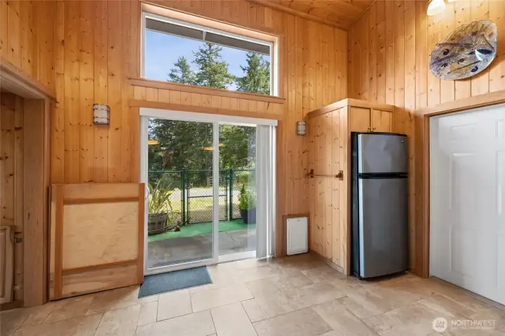 Large room between kitchen and garage has access to deck and extra refrigerator.