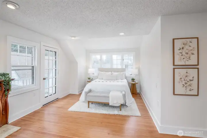 This primary bedroom features its own balcony overlooking the pretty backyard.