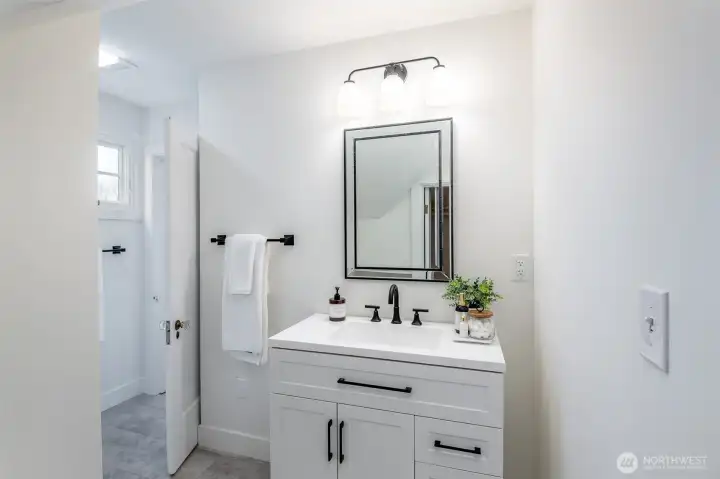This updated bathroom includes a new vanity, lighting, tile, toilet, and flooring.