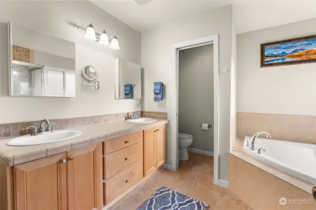 The en-suite boasts double sinks, a relaxing soaking tub, a spacious glass-enclosed shower, and the added convenience of a private toilet room for ultimate privacy.