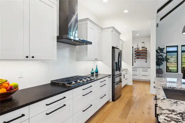 Look at that stunning tile backsplash! So much storage here. Quality Belmont Cabinetry, gas (propane) range, leathered charcoal granite (gorgeous), Allwood engineered flooring.