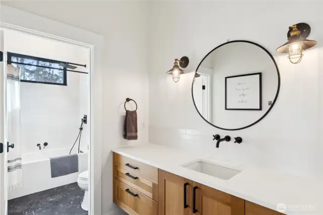 Ensuite bathroom for guest bedroom #1. It offers floating vanity, heated tile flooring, quality hardware and tile tub surround. Stunning.