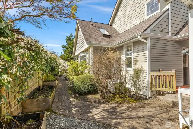Side yard of home shows the raised beds and the privacy between the homes.  Closing off the gate, allows pets to enjoy the yard and the view of the golfers!