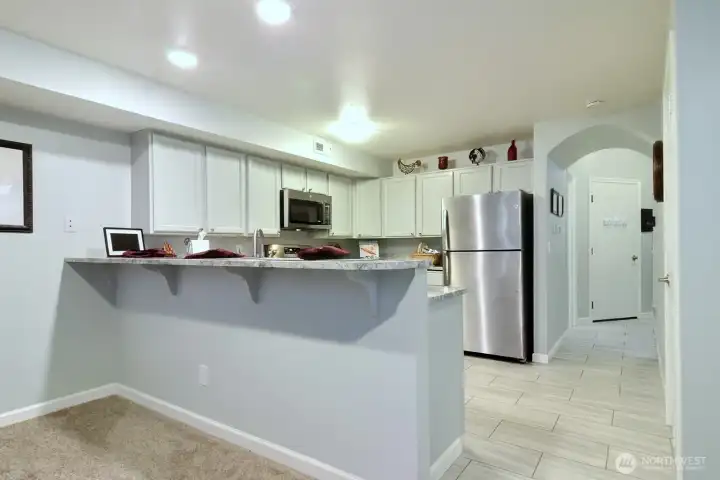 One view of the remodeled kitchen showing the breakfast bar and the new tile flooring in the kitchen, hallway and half bath